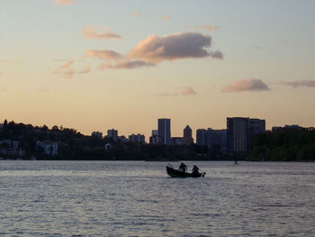 Scenic view of river and buildings against sky during sunset