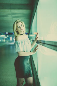 Portrait of young woman standing by window