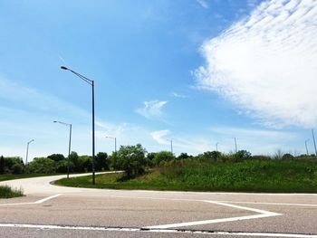 Street by field against sky