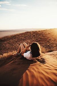 Woman lying on sand during sunny day
