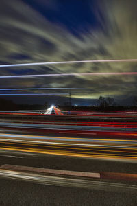 Light trails on road against sky at night