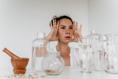 Portrait of young woman in bottles against white background