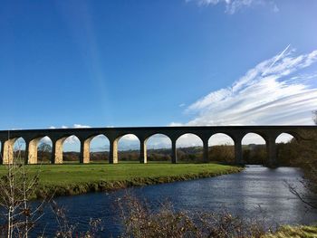 Arch bridge over river against sky