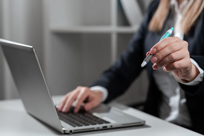 Midsection of businessman using laptop on table