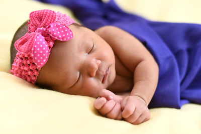 Close-up of baby girl sleeping on bed at home