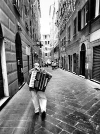 Rear view of man with accordion walking on street