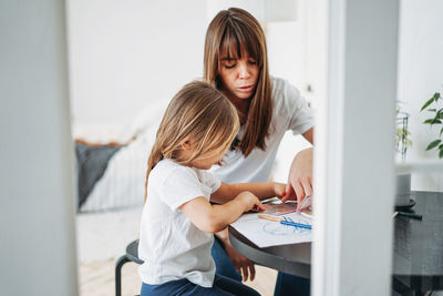 Mother assisting daughter drawing on paper