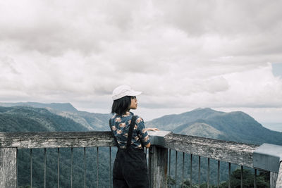 Rear view of man standing on mountain against sky