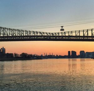 Suspension bridge over river at sunset