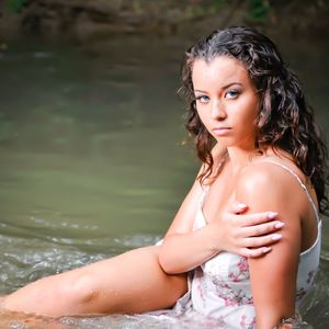 Portrait of young woman sitting against water