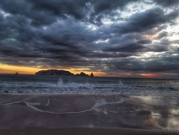 Scenic view of beach against cloudy sky