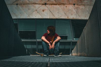 Full length of young man sitting outdoors