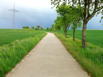 Road amidst field against sky