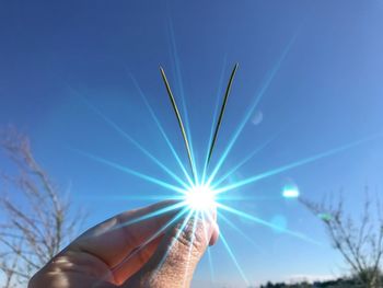 Optical illusion of hand holding sun against blue sky