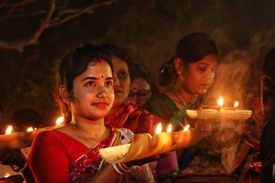 Women holding dia-oil lamp on hand at a smokey background in rakher upobash baradi 