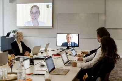 Male and female professionals having video conference meeting in board room at office