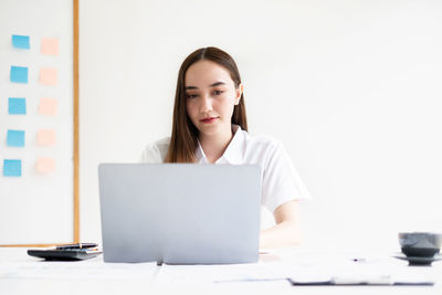 Businesswoman using laptop while sitting on table