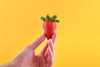 Midsection of person holding ice cream cone against orange background