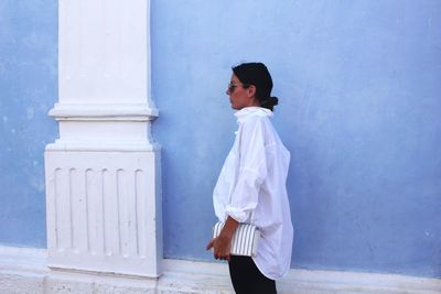 Portrait of young woman standing against wall