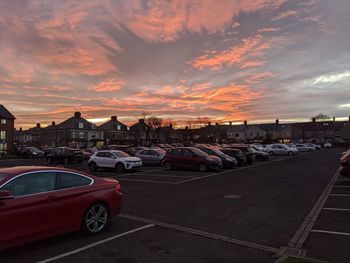 Cars on road in city against sky at sunset