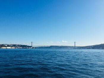 Bridge over sea against clear blue sky