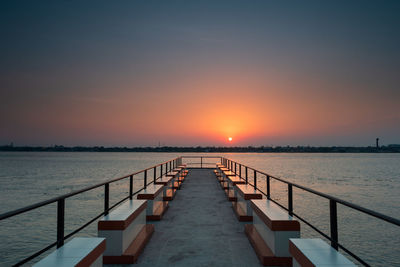 Pier over sea against sky during sunset