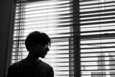 Portrait of man standing by window at home