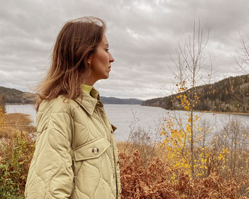 Young woman standing against lake