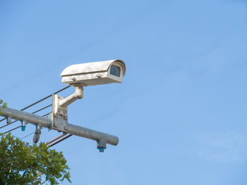 Low angle view of telephone pole against clear blue sky