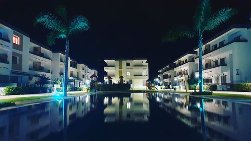 Illuminated buildings by swimming pool at night