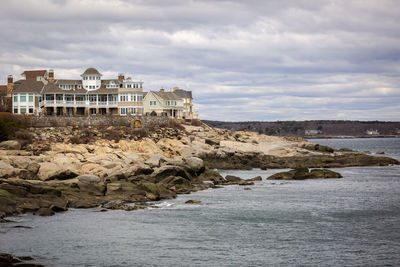 Buildings by sea against sky