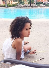 Thoughtful girl looking away while sitting at poolside