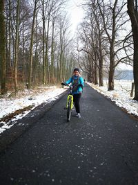 Man riding bicycle on road in forest