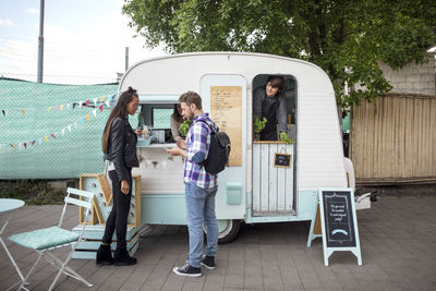 Side view of customers standing outside food truck on street