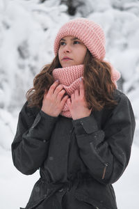 Low section of woman wearing hat standing in snow