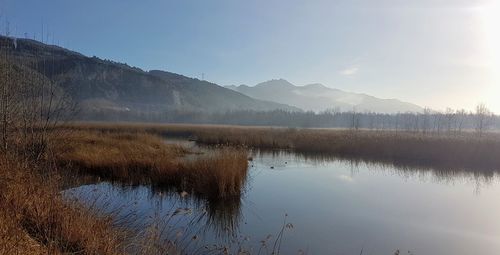 Scenic view of lake by mountains against sky