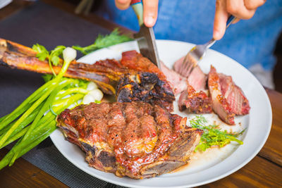 A man cuts cooked fried meat in a plate. oven-roasted meat for dinner. close-up