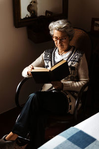 Elderly woman reading by window with enthusiasm