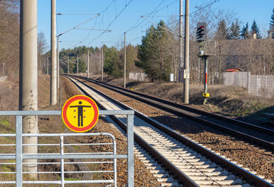 Information sign by railroad tracks against sky