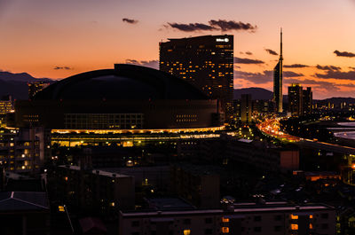 Illuminated buildings in city at sunset