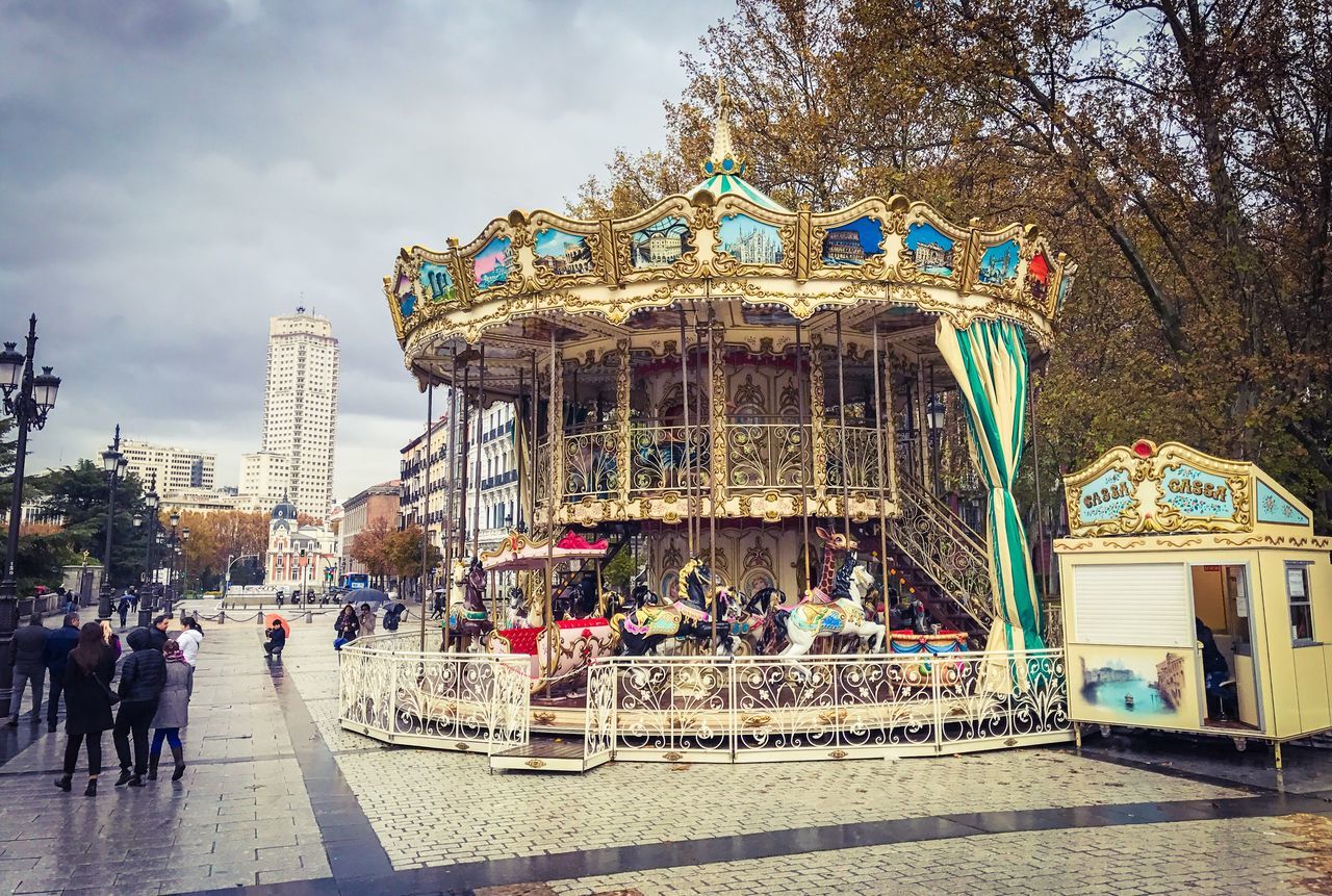 multi colored, sky, building exterior, outdoors, cloud - sky, leisure activity, built structure, amusement park ride, city, architecture, day, real people, carousel, men, amusement park