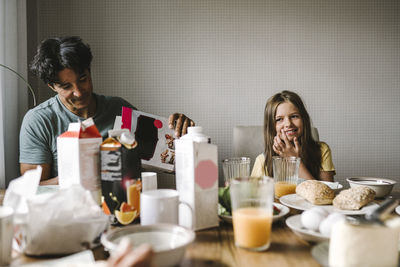 Smiling father and daughter having breakfast together at dining table