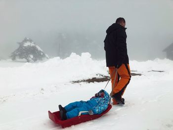 Father with son sledding on snowy field