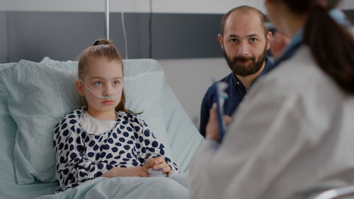 Doctor having conversation with father and daughter at hospital