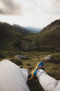 Low section of man on mountain against sky