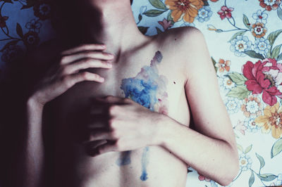 Close-up of man with paint on chest lying at bed