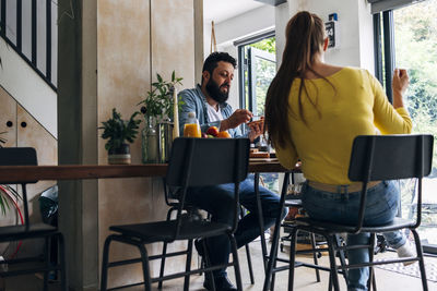 Man having breakfast with woman while sitting at home