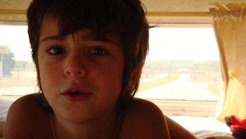 Portrait of boy looking through window at home