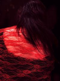 Rear view of woman with red hair against black background