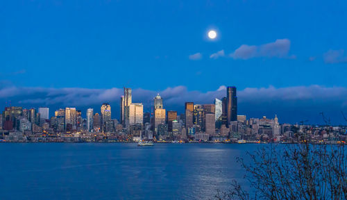 A bright full moon shines over the seattle skyline.